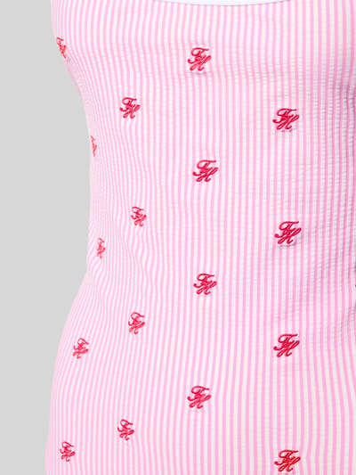 Frauenmodel trägt Badeanzug mit Neckholder von TOMMY HILFIGER, rosa-weiß gestreifter Seersucker mit Logo-Stitching, Nahaufnahme Oberkörper.