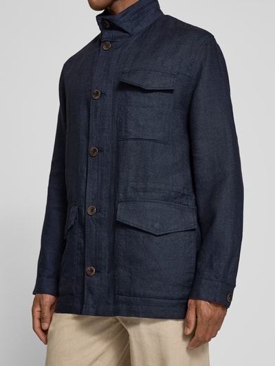Męski model nosi Leinenjacke mit Stehkragen und Pattentaschen von bugatti, granatowy, krój regular fit, czysty len, z patkami, zapięcie na guziki, długość tyłu w rozmiarze 50: 74 cm, szerokość ramion w rozmiarze 50: 46 cm, szerokość klatki piersiowej w rozmiarze 50: 55 cm, długość rękawa w rozmiarze 50: 64 cm, tekstura gładka, widok przód w półzbliżeniu.
