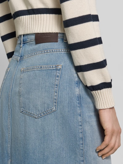 Kobiece model prezentuje spódnica jeansowa Ausgestellter Jeansrock aus reiner Baumwolle od Marc O'Polo, denim, aplikacja z logo, nity, szlufki na pasek, otwarty dół, 5 kieszeni, bawełna, detaliczne ujęcie tylnej części.