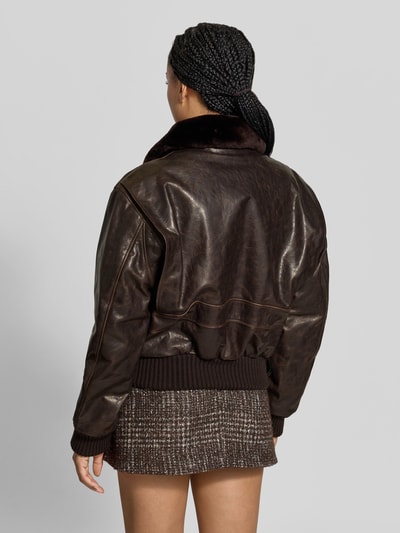 Frauenmodel trägt Lederjacke mit Umlegekragen von Victoria Beckham in Dunkelbraun, authentische Lederstruktur, Rückansicht, Ganzkörperansicht von hinten. Relaxed Fit, aufgesetzte Taschen, Reißverschluss, Länge 56 cm, Brustweite 52 cm, Ärmellänge 62 cm.