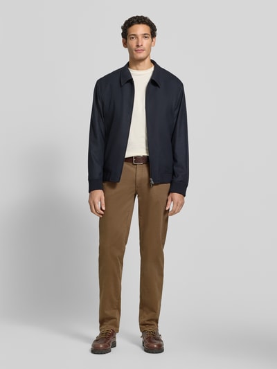 Männermodel trägt Regular Fit Weite Hose aus Baumwoll-Mix mit Lyocell-Anteil von Brax, Herren Weite Hose, braun, glatte Textur, Ganzkörperansicht von vorne.
