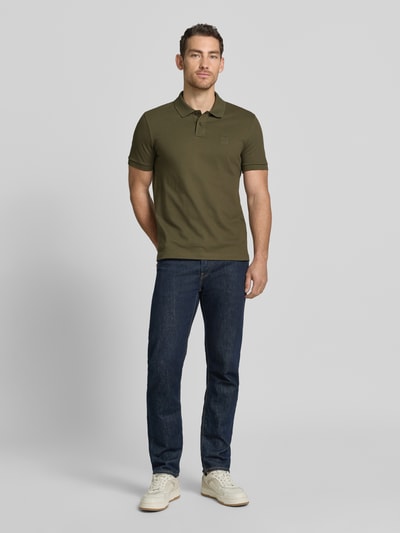Męski model nosi koszulkę polo Slim Fit Poloshirt aus Baumwoll-Mix Modell 'PASSENGER' von BOSS Orange, efekt: jednolity kolor, krój slim fit, naszywka z logo, kołnierzyk polo, zapięcie na 2 guziki, krótki rękaw, mieszanka bawełny, Ganzkörperansicht von vorne.