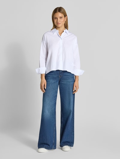 Kobiece model nosi Relaxed Fit bluzkę z wydłużonym tyłem model 'CLOELIA' od Drykorn, z czystej bawełny, kołnierzyk koszulowy, niebiesko-biała, długość tyłu 66 cm, długość rękawów 52 cm, krój relaxed fit, bluzka, widok całej sylwetki z przodu.