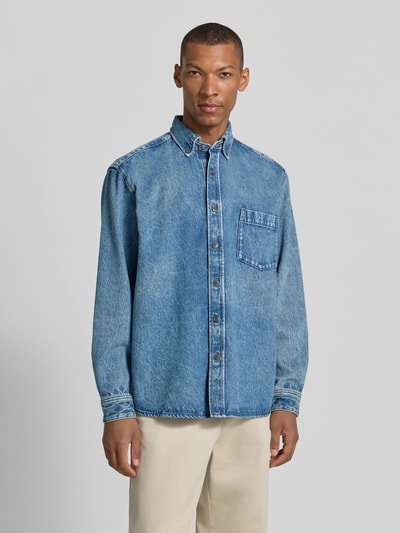 Männermodel trägt Regular Fit Jeansjacke aus reiner Baumwolle Modell 'LAMBEY BO FLEAK' von BOSS Orange, Denim-Optik, Ganzkörperansicht von vorne.