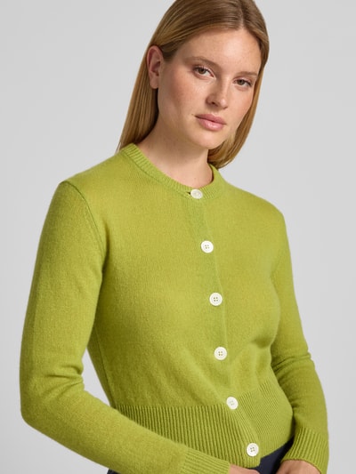 Frauenmodel trägt Strickjacke aus Kaschmir mit Rundhalsausschnitt Modell 'Karina' von JOOP! in Slim Fit, leuchtend grün, Nahaufnahme Oberkörper. Reiner Kaschmir, Knopfleiste, feine Textur, Rückenlänge 54 cm, Ärmellänge 70 cm.