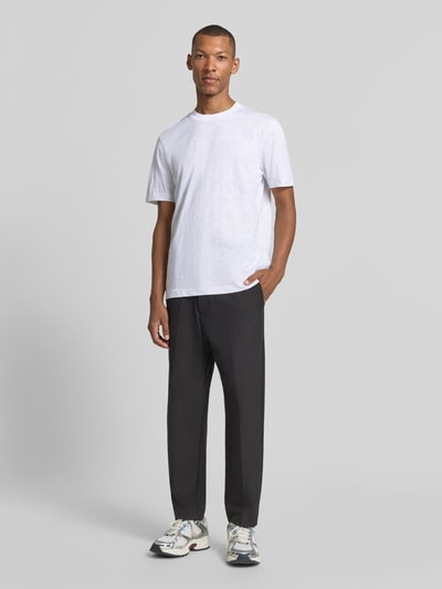 Männermodel trägt weißes Regular Fit T-Shirt aus reiner Baumwolle von BOSS Green zu dunkler Hose, Ganzkörperansicht von vorne.