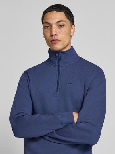 Männermodel trägt Regular Fit Sweatshirt aus Baumwoll-Mix von Tommy Jeans in Dunkelblau mit glatter Textur, Nahaufnahme Oberkörper. Herren Sweatshirt von Tommy Jeans