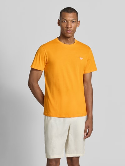 Männermodel trägt T-Shirt mit Logo-Patch und Rundhalsausschnitt von Emporio Armani in Orange, Modern Fit, reine Baumwolle, Ganzkörperansicht von vorne.