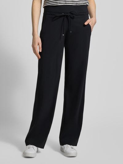 Frauenmodel trägt Straight Leg Jogpants aus Hightech Jersey Modell 'CANDICE' von Raffaello Rossi, Schwarz, elastischer Bund mit Schnürung, Ganzkörperansicht von vorne.
