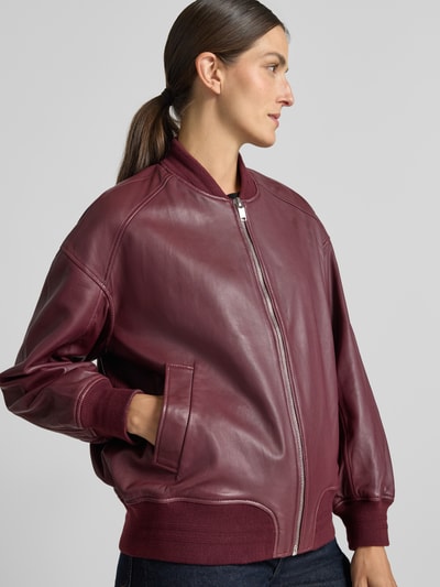 Frauenmodel trägt Regular Fit Bomberjacke aus reinem Schafsleder Modell 'Ruby' von MOS MOSH, bordeaux, glatte Textur, Eingrifftaschen, Reißverschluss, elastische Abschlüsse, Nahaufnahme Oberkörper.
