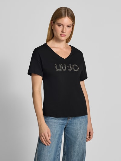 Frauenmodel trägt Regular Fit T-Shirt aus reiner Baumwolle von Liu Jo White in Schwarz mit Ziersteinbesatz und Logo-Detail, Ganzkörperansicht von vorne.