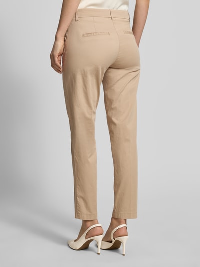 Frauenmodel trägt Hose in verkürzter Passform Modell 'MARON' von Brax aus beige Baumwoll-Mix mit Lyocell, Ganzkörperansicht Rückansicht.