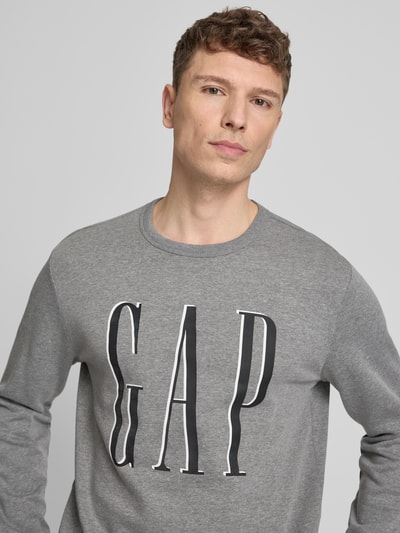 Männermodel draagt Sweatshirt mit Logo van GAP in grijs, katoenmix, regular fit, ronde hals, logoprint, nahaufnahme bovenlichaam.