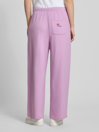 Vrouwenmodel draagt sweatpants met elastische band model 'ATUBAY' van American Vintage, mix van katoen en elastaan, wide leg, binnenbeenlengte bij maat M 70 cm, tunnelkoord, lichtroze kleur, full body achteraanzicht.