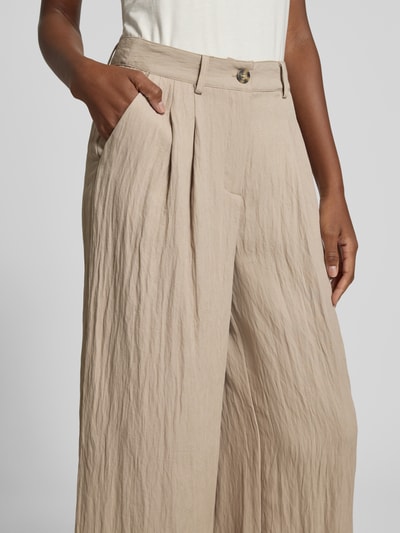 Frauenmodel trägt Culotte mit Knopf- und Reißverschluss Modell 'Milo' von LOLLYS LAUNDRY, Material-Mix mit Viskose-Anteil, Wide Leg Fit, seitliche Eingrifftaschen, beige, leicht strukturierte Textur, Nahaufnahme Oberkörper.