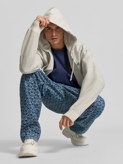 Männermodel trägt Relaxed Fit Jeans aus reiner Baumwolle von KENZO in Blau mit grafischem Muster, 5-Pocket-Design, Ganzkörperansicht von vorne.