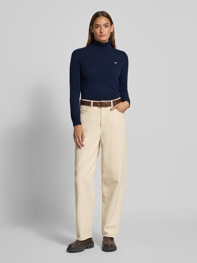 Modelka nosi Regular Fit Rollkragenpullover aus Woll-Mix Modell 'Extrafine' od Gant, granatowy, dzianinowa faktura, logo, damski sweter, krój regular fit, długość tyłu 58 cm, długość rękawa 62 cm, widok całej sylwetki z przodu.