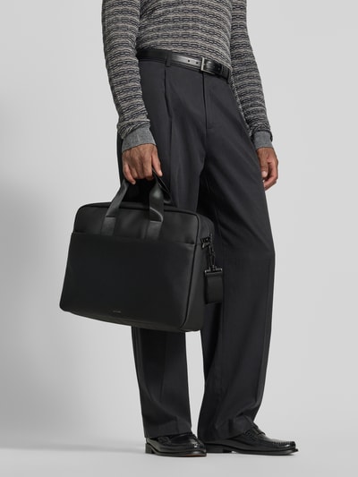 Mężczyzna nosi czarny plecak Aktentasche mit Label-Prägung Modell 'lanciano' od JOOP! COLLECTION, widok całej sylwetki z przodu