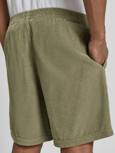 Männermodel trägt Shorts mit elastischem Bund Modell 'PADOW' von American Vintage in Olive, Cordstruktur, Loose Fit, Rückansicht Detailaufnahme.