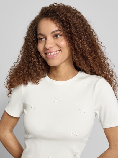 Frauenmodel trägt Slim Fit T-Shirt aus Baumwoll-Mix Modell 'FEMKE' von Only, unifarben, Schleife-Details, Feinripp, Nahaufnahme Oberkörper.
