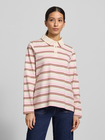 Frauenmodel trägt Poloshirt aus reiner Baumwolle von Soyaconcept in Creme mit rosa und roten Streifen, gerader Schnitt, Ganzkörperansicht von vorne.