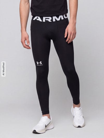 Männermodel trägt schwarze Slim Fit Sport-Leggings mit Logo-Print von Under Armour, glatte Textur, Ganzkörperansicht von vorne, KI-modifiziertes Bild.