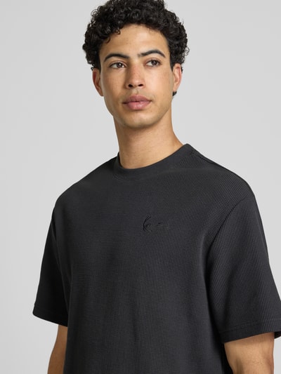 Männermodel trägt Oversized T-Shirt mit Strukturmuster und Logo-Stitching von KARL KANI, Baumwoll-Mix, Oversized-Fit, Rundhalsausschnitt, Rückenlänge 75 cm, Nahaufnahme Oberkörper.