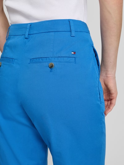 Vrouwenmodel draagt Slim Fit Chino aus Baumwoll-Mix van Tommy Hilfiger in effen blauw met zijzakken en achterzakken, detailopname rugaanzicht.