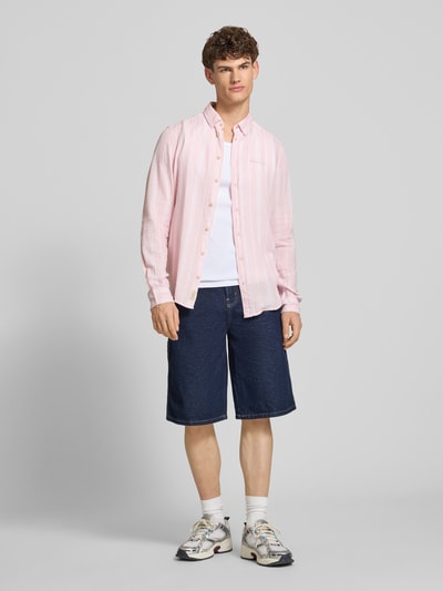 Männermodel trägt Regular Fit Leinenhemd mit Viskose-Anteil Modell 'Bobby' von Blend in Rosa, Kentkragen, Jeansshorts, Ganzkörperansicht von vorne