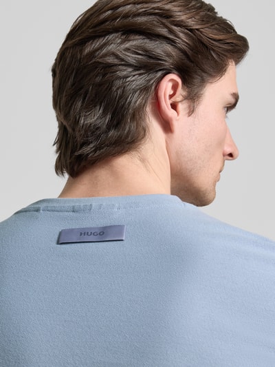 Männermodel trägt Regular Fit T-Shirt aus reiner Baumwolle Modell 'DIMERSTESO' von HUGO in Hellblau mit Label Stitching, Detailaufnahme Rückansicht