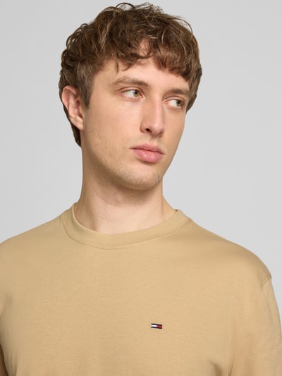 Männermodel trägt Regular Fit T-Shirt aus reiner Baumwolle von Tommy Jeans, Optik: Unifarben, Logo-Stitching, Rundhals, Jersey, Nahaufnahme Oberkörper.