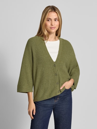 Kobiece model prezentuje kardigan z elastycznej mieszanki materiałów z bawełną, krój oversized fit, listwa guzikowa, dekolt w serek, imitacja dzianiny, długość tyłu 63 cm, długość rękawów 35 cm, Model 'DAMSVILLE' od American Vintage, widok całej sylwetki z przodu.