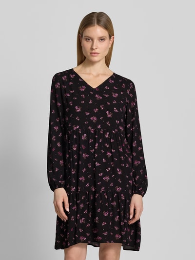 Frauenmodel trägt Minikleid aus Viskose mit V-Ausschnitt von Zero in Schwarz mit pinkem Blumenmuster, taillierter Schnitt, elastische Ärmelabschlüsse, Rückenlänge 80 cm, Brustweite 39 cm, Ärmellänge 60 cm, Ganzkörperansicht von vorne.