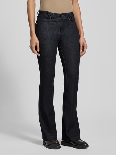 Frauenmodel trägt Flared Fit Jeans im 5-Pocket-Design Modell 'Shakira' von BRAX aus elastischem Baumwoll-Mix, dunkle Farbe, Ganzkörperansicht von vorne.