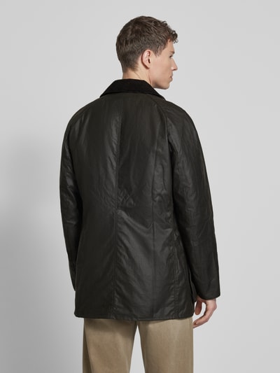 Männermodel trägt Original Wachsjacke von Barbour in dunklem Grünton mit gewachste-Baumwolle-Mix, vollständig gefüttert, klassischer Cordkragen, aufgesetzteTaschen mit Druckknopf, ganzkörperansicht rückansicht.