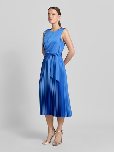 Modelka nosi Midikleid mit Plisseefalten und Bindegürtel von comma, mieszanka materiałów z dodatkiem streczu, linia a, plisy, wiązany pasek, długość tyłu w rozmiarze 36: 35 cm, szerokość w rozmiarze 36: 40 cm, kolor niebieski, gładka faktura. Ganzkörperansicht z przodu.