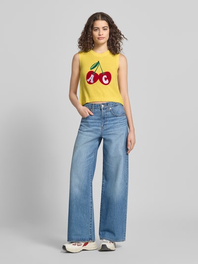Frauenmodel trägt Regular Fit Weste mit Logo-Stitching von ANOTHER COTTON LAB in Strick-Optik, Rundhalsausschnitt, leuchtendes Gelb, Ganzkörperansicht von vorne.