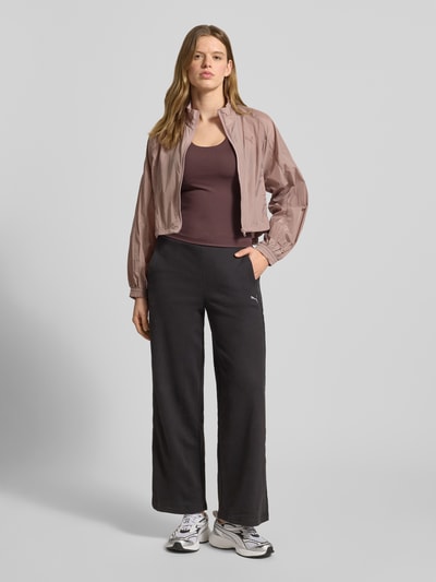 Frauenmodel trägt Slim Fit Top mit integriertem Bustier von PUMA, Elastischer-Material-Mix, Logo-Print, Ärmelloses-Design, Rundhalsausschnitt, Rückenlänge 44 cm, Farbkontrast mit schwarzer Hose, Ganzkörperansicht von vorne.