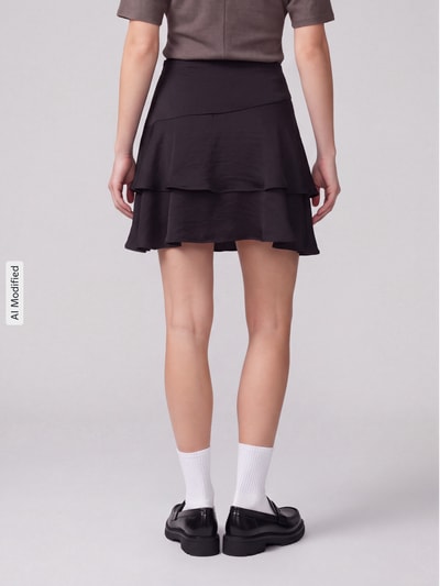 Frauenmodel trägt schwarzen A-Linien Mini-Rock mit Volants Modell 'MIRO' von VERO MODA, Damen Mini-Rock, Ganzkörperansicht Rückansicht, KI-modifiziertes Bild.