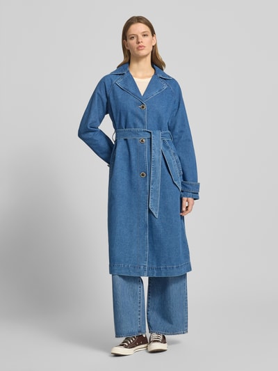 Vrouwenmodel draagt Loose Fit Trenchcoat aus Denim model 'MALOU' van Only, denimlook in blauw, katoenmix, contrastnaden, strookzakken, lange mouw, reverskraag, knoopsluiting, tailleriem, ganzlichaamsaanzicht van voren.