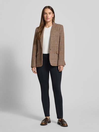 Kobiece modelka nosi spodnie materiałowe w skróconym fasonie model 'Sydney' od Marc Cain, mieszanka materiałów z dodatkiem streczu, prosty krój, detal z logo, zapięcie na guzik i zamek błyskawiczny, czarny kolor, gładka tekstura, widok całej sylwetki z przodu.