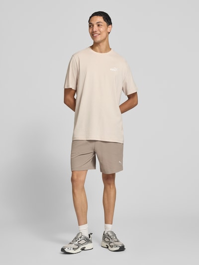 Männermodel trägt Regular Fit T-Shirt mit Logo-Stitching von PUMA PERFORMANCE in Beige, reine Baumwolle, Rundhalsausschnitt, Ganzkörperansicht von vorne.