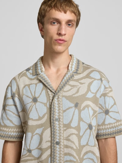 Männermodel trägt mehrfarbiges Relaxed Fit Freizeithemd aus Baumwoll-Mix Modell 'DUKE' von Only & Sons mit floralem Muster, Nahaufnahme Oberkörper.