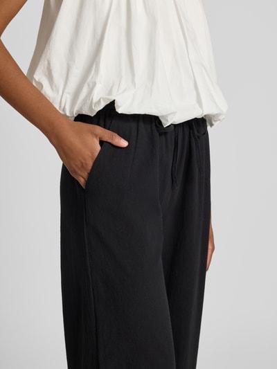 Frauenmodel trägt schwarze Stoffhose in verkürzter Passform Modell 'CISSIE' von Soyaconcept aus reiner Baumwolle mit Tunnelzug, Nahaufnahme Oberkörper.