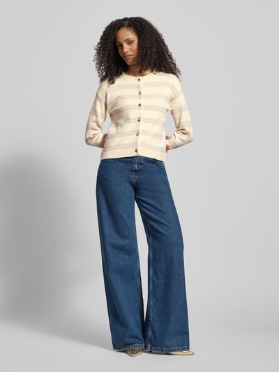 Frauenmodel trägt Regular Fit Cardigan aus Viskose-Mix Modell 'GOLD STRIPE' von Vero Moda in Two-Tone-Optik mit Streifenmuster, Knopfleiste, Rundhalsausschnitt, Langarm und gerippten Abschlüssen, Strick, Optik: Unifarben, Label-Stitching-Applikation, Ganzkörperansicht von vorne.
