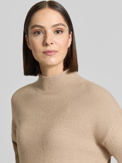 Frauenmodel trägt Turtleneck-Pullover mit Woll-Anteil und Rundhalsausschnitt von Neo Noir, beige, feine Strickstruktur, Nahaufnahme Oberkörper.