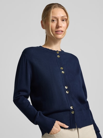 Frauenmodel trägt Cardigan aus Viskose-Mix von MORE & MORE in Dunkelblau mit Goldknöpfen, Strick-Optik, Nahaufnahme Oberkörper.