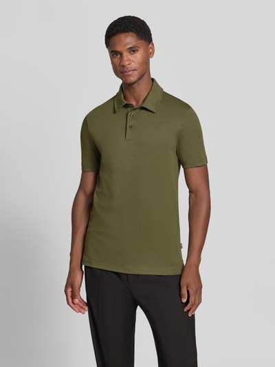Męski model nosi oliwkową koszulkę polo z bawełny Regular Fit model 'Palosh 30' od BOSS, proste czarne spodnie, Ganzkörperansicht von vorne. Koszulka polo męska od BOSS.