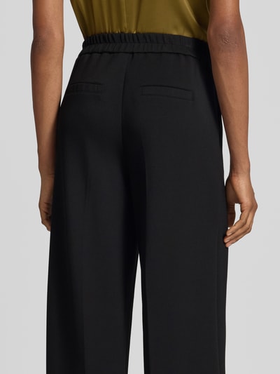 Männermodel trägt czarne szerokie spodnie Regular Fit z mieszanki modalu Regular Fit Weite Hose aus Modal-Mix Modell 'BELLIS' von VERO MODA, Damen Weite Hose, Ganzkörperansicht Rückansicht