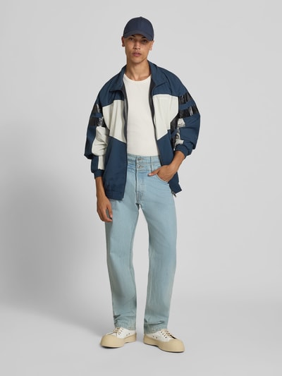 Männermodel trägt Regular Fit Jeans mit Label-Detail von VETEMENTS aus Reiner Baumwolle, hellblau, 5-Pocket-Design, Ganzkörperansicht von vorne.